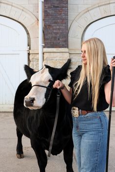 a woman is walking her cow down the street