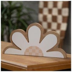 a wooden card with a white flower on it sitting on a table next to a chair