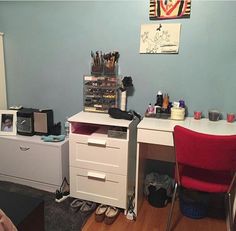 a bedroom with a desk, chair and other items on it in front of a blue wall