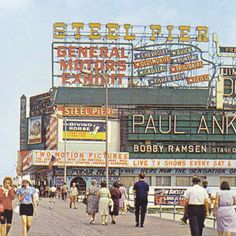 an old photo of people walking on the boardwalk in front of some shops and stores