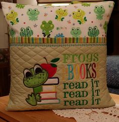 a pillow with frog books on it and an apple sitting on top of the pillow