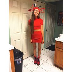 a woman in a red dress with a crab on her head standing next to a door