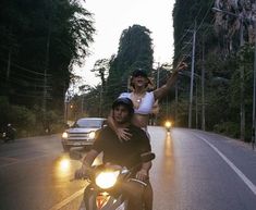 a man and woman riding on the back of a motorcycle down a street at night