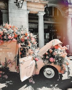 an old pink truck with flowers on the back