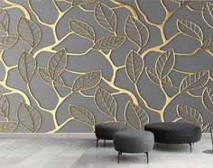 two black chairs sitting in front of a wall with gold leaves on it