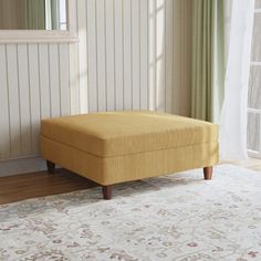 a yellow footstool sitting on top of a rug in front of a window