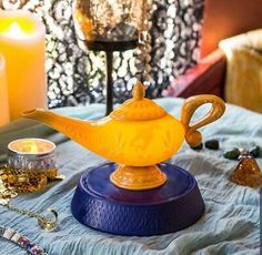 a yellow teapot sitting on top of a table next to candles and other items