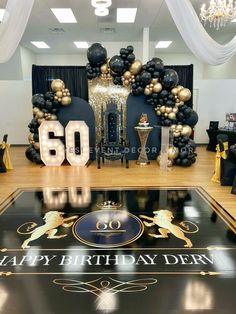 a 50th birthday party with black and gold decorations, balloons and streamers on the floor