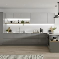 a modern kitchen with grey cabinets and white counter tops, an area rug and potted plants