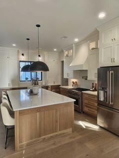 a modern kitchen with stainless steel appliances and wooden cabinets, along with an island in the middle