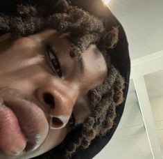 a man with dreadlocks sticking his tongue out in front of the camera lens