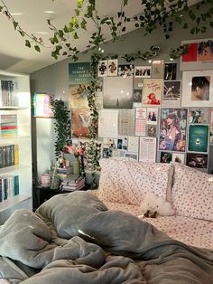 an unmade bed in a bedroom with lots of pictures on the wall behind it