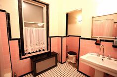 a bathroom with pink and black tiles, sink, toilet and window in the corner