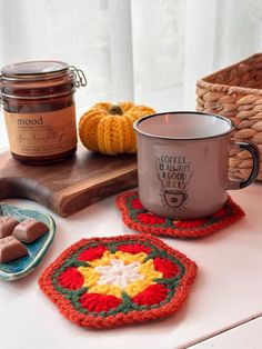 two coffee mugs on a table with some crocheted coasters