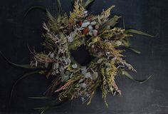 a wreath with dried flowers and leaves on a black background