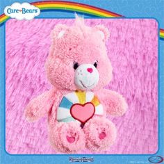 a pink teddy bear with a heart on it's chest sitting in front of a rainbow background