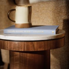 a stack of books sitting on top of a wooden table next to a coffee cup