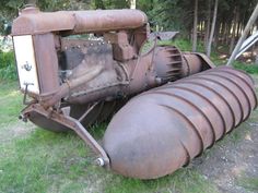 an old tractor sitting in the grass with its front end turned upside down on it's side