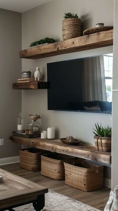 a flat screen tv mounted on a wooden shelf in a living room next to baskets