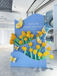 a blue sign with yellow flowers and butterflies on it