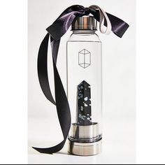 a glass bottle with a black ribbon tied around it and an object in the bottom