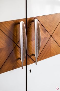 two metal objects mounted to the side of a white cabinet with wood panels on it