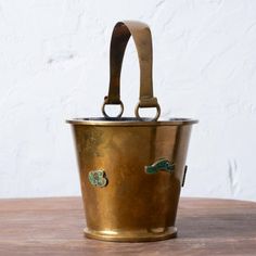 an old brass bucket sitting on top of a wooden table