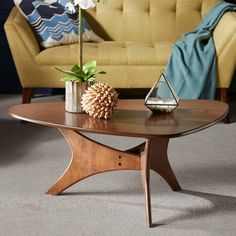 a living room with a couch, coffee table and potted plant on the floor