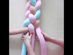 two hands are pulling a large pink and blue braid out of the wall with one hand