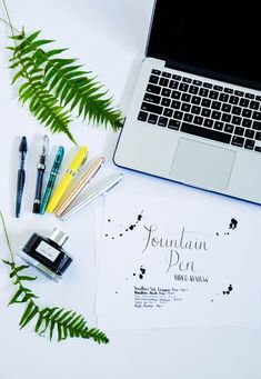 an open laptop computer sitting on top of a desk next to some pens and markers