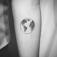 a person with a small tattoo on their arm that has the earth in it's center