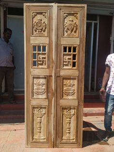 a man standing in front of a wooden door with carvings on the doors and sides