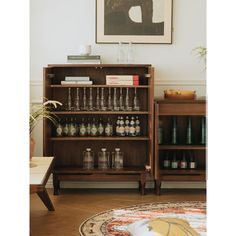 a wooden shelf filled with lots of bottles and glasses next to a painting on the wall