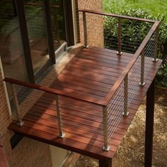 a wooden deck with metal railings next to a brick building