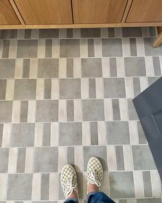 a person standing on a tiled floor with their feet up