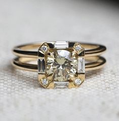 an engagement ring with a yellow diamond and baguettes on the side, sitting on a white surface