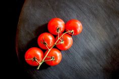 four tomatoes sitting on top of a black surface