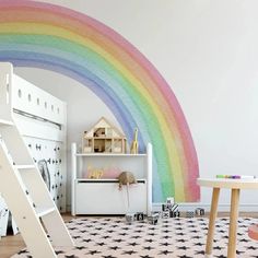 a child's room with a rainbow painted on the wall and a ladder in front of it