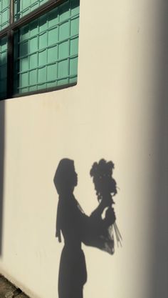 a shadow of a woman holding flowers on the side of a building