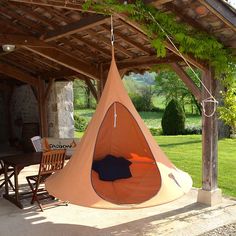 a tent that is hanging from the ceiling in front of a table with chairs on it