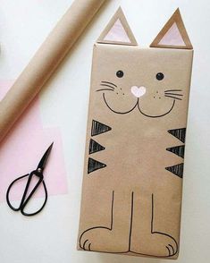 a paper bag with a cat on it next to scissors and other crafting supplies