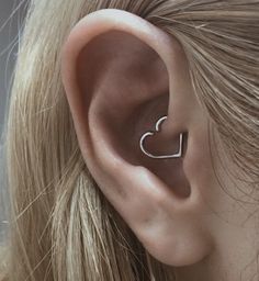 a close up of a person's ear with a heart shaped nose piece in the middle