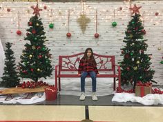 a woman sitting on a bench in front of christmas trees