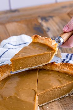 a person holding a knife cutting into a peanut butter pie on top of a wooden table