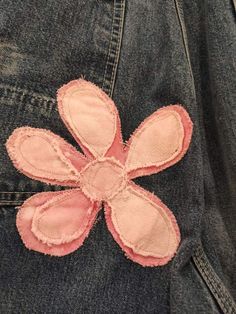 a pink flower is on the back of a jean jacket