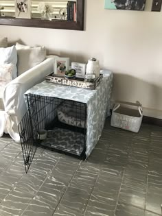 a dog crate sitting on top of a floor next to a white couch and mirror