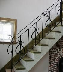 a stair case next to a brick fireplace in a room with white walls and black iron railings