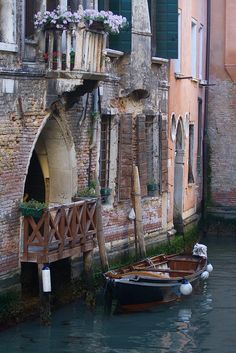 two boats are tied to the side of an old brick building in venice, italy