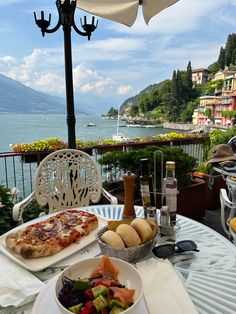 a table topped with plates of food next to an umbrella covered patio overlooking the ocean