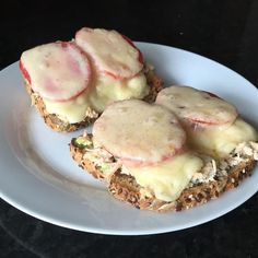 three sandwiches with meat and cheese on them are sitting on a plate, ready to be eaten